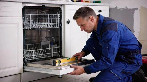 Technician using a spirit level to check a dishwasher installation