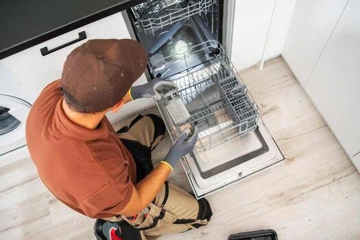 Technician inspecting the racks and interior of an open dishwasher
